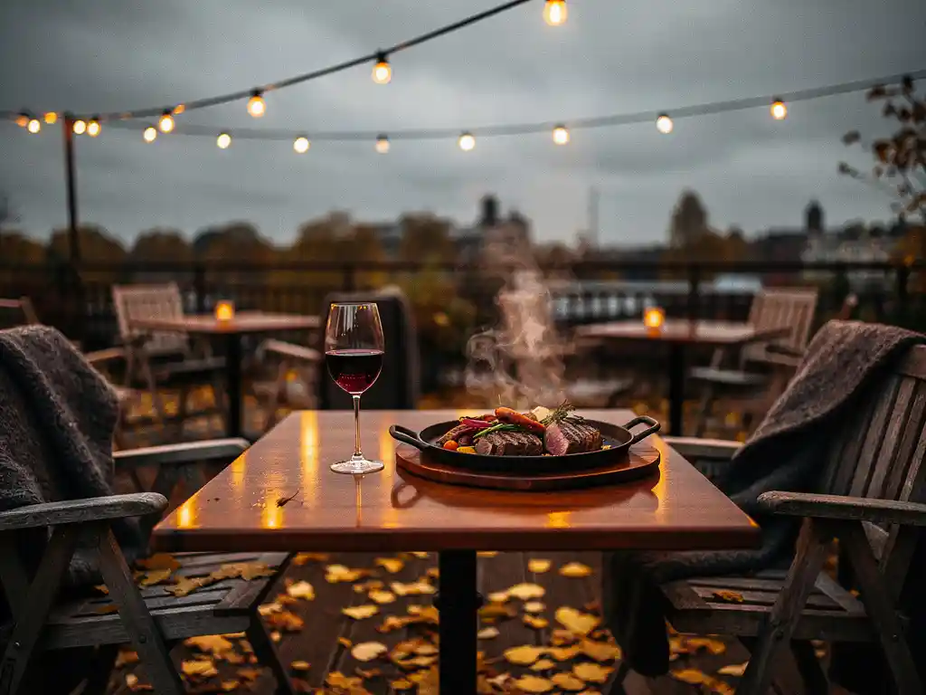 Verwarmd terras in Amsterdam met wollen dekens, gouden herfstbladeren, een glas rode wijn en gietijzeren bord onder sfeervolle amberkleurige lichtjes.